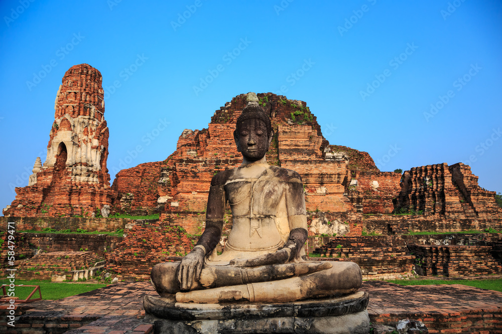ancient big Buddha statue in front of damaged brick pagoda on bl ancient big Buddha statue in front of damaged brick pagoda on bl
