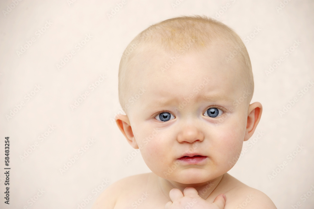 Baby looking at the camera on a peach background