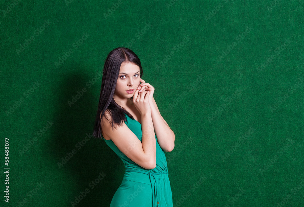 brunette in green dress against wall