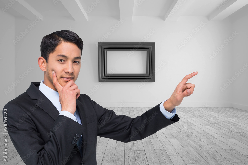 Composite image of thoughtful asian businessman pointing