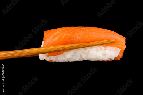 holding sushi with chopsticks isolated on black