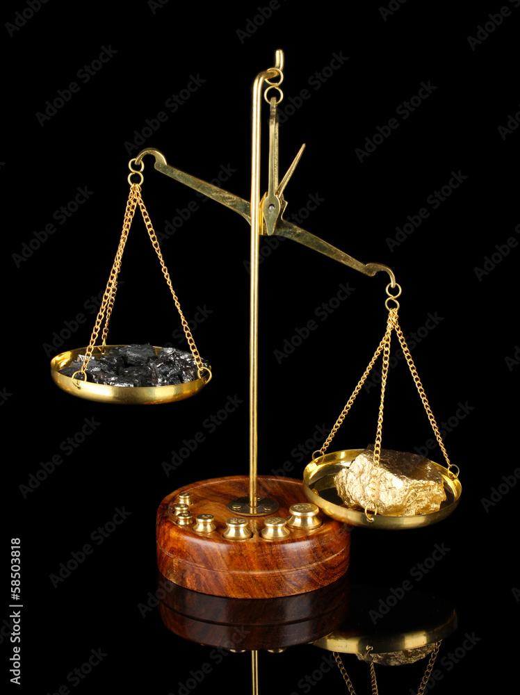 Gold and coal on scales on dark grey background Gold and coal on scales on dark grey background