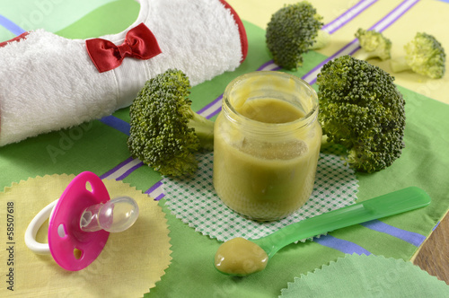 Baby food still life with broccoli puree and bib