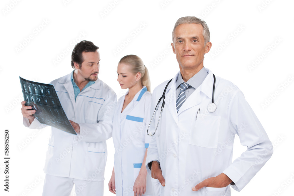 Confident and experienced Head physician on foreground. Confident and experienced Head physician on foreground.