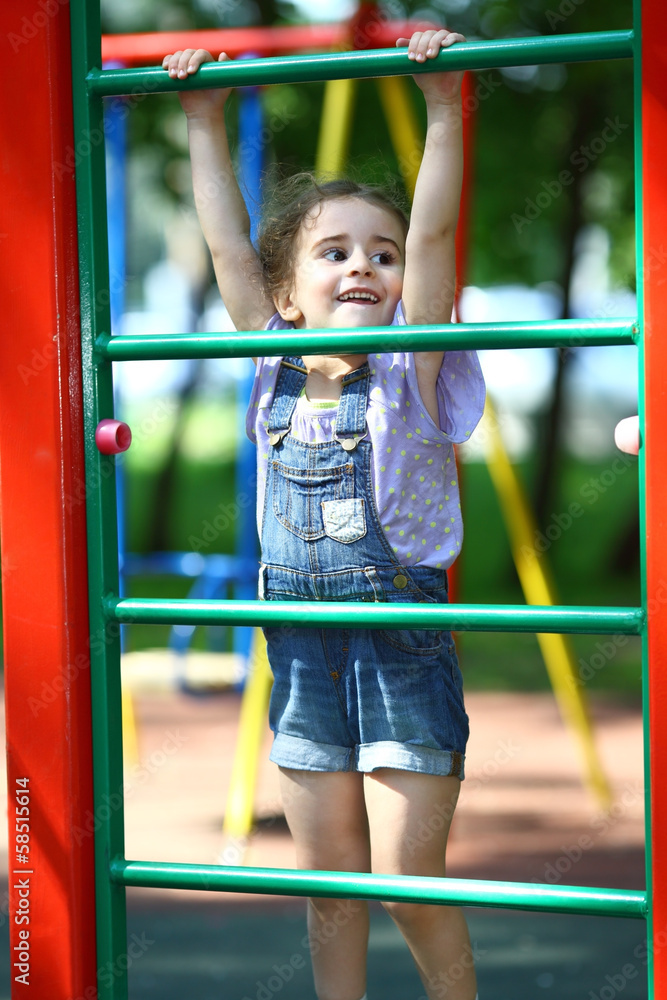 Happy girl hanging on gymnastic wall on playground Happy girl hanging on gymnastic wall on playground