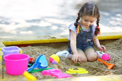 Little girl sitting in sandbox and playing with molds © Pavel Losevsky