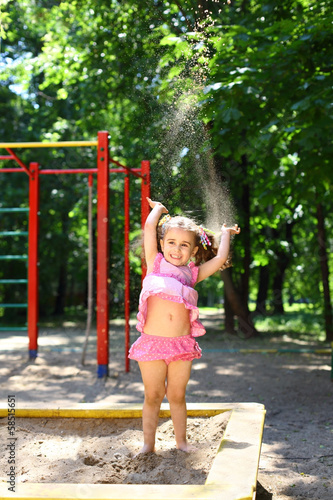 Little girl throws up sand in the sandbox