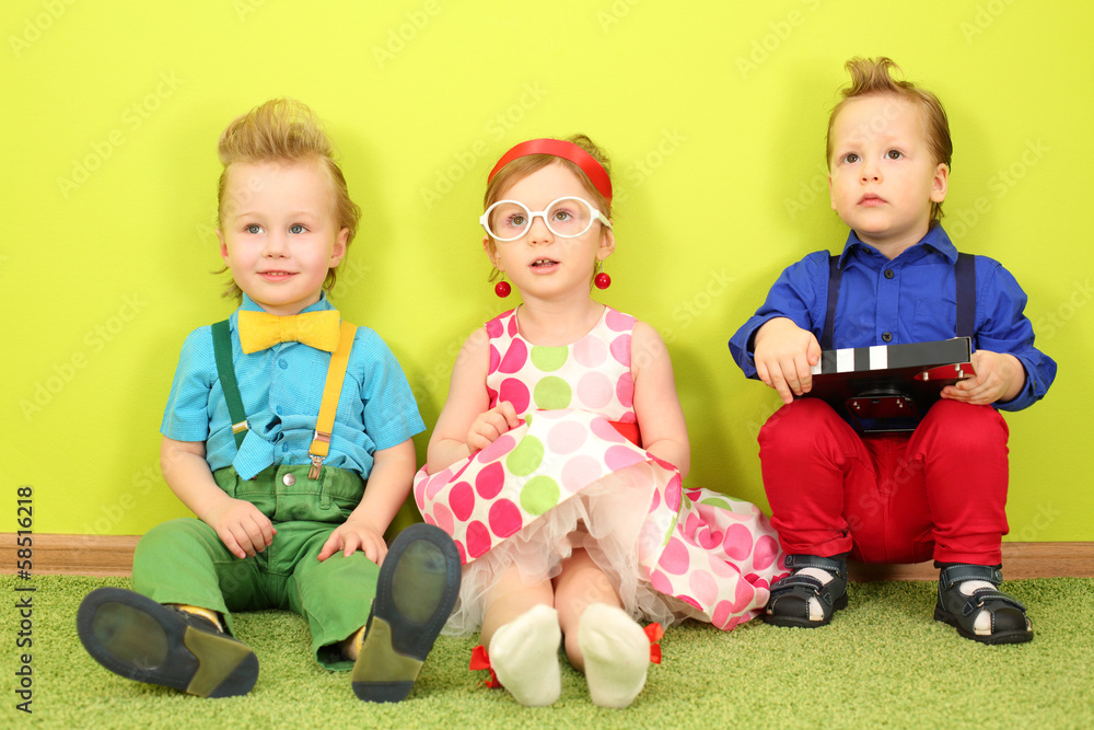 Three mods children in bright clothes sitting at the wall Three mods children in bright clothes sitting at the wall