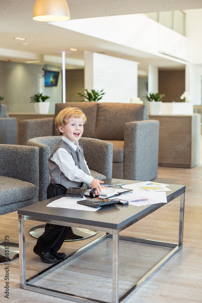 little boy in tie with stationery on table in business center little boy in tie with stationery on table in business center