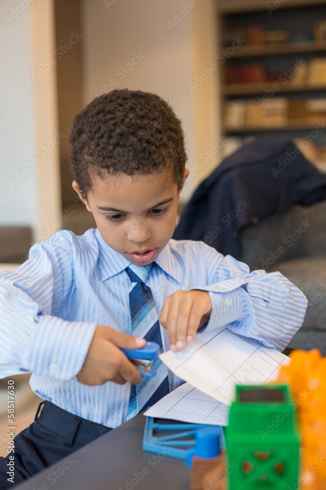 A little boy is holds stapler paper in business center