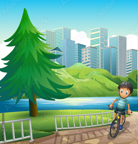 A boy biking across the tall buildings near the river