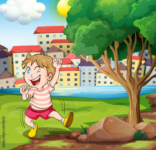 A happy kid near the tree at the riverbank beside the tall build