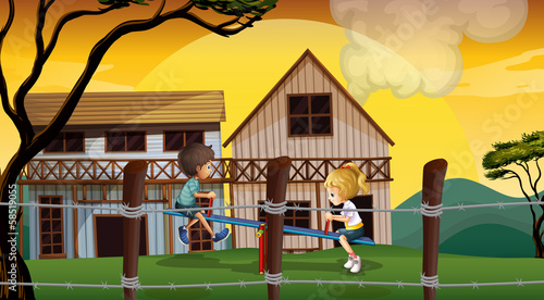 Kids playing seesaw in front of the wooden barnhouses photo