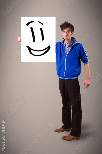 Young boy holding smiley face drawing