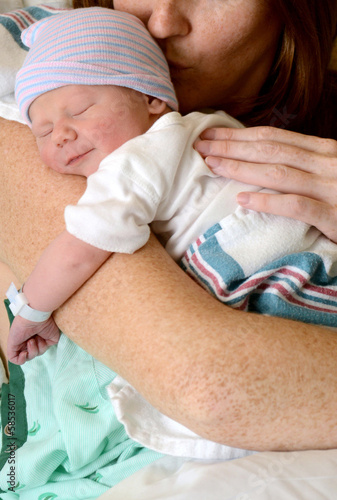 Fotografie mother kissing smiling newborn baby