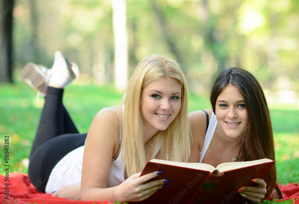 Fototapeta premium Two girls reading book in park