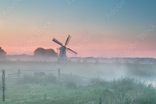 Dutch windmill in summer morning fog photo