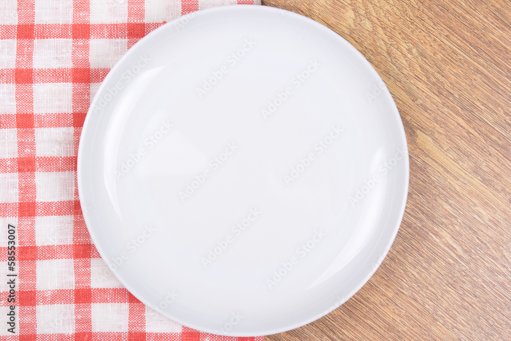 empty plate on the wooden table with checkered tablecloth empty plate on the wooden table with checkered tablecloth