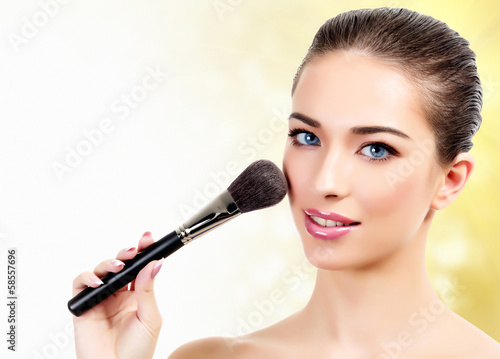 woman with cosmetic brushes against an abstract blurred backgrou