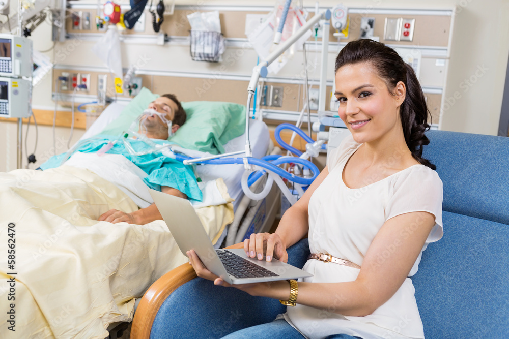 Woman With Laptop Sitting By Male Patient In Hospital Woman With Laptop Sitting By Male Patient In Hospital