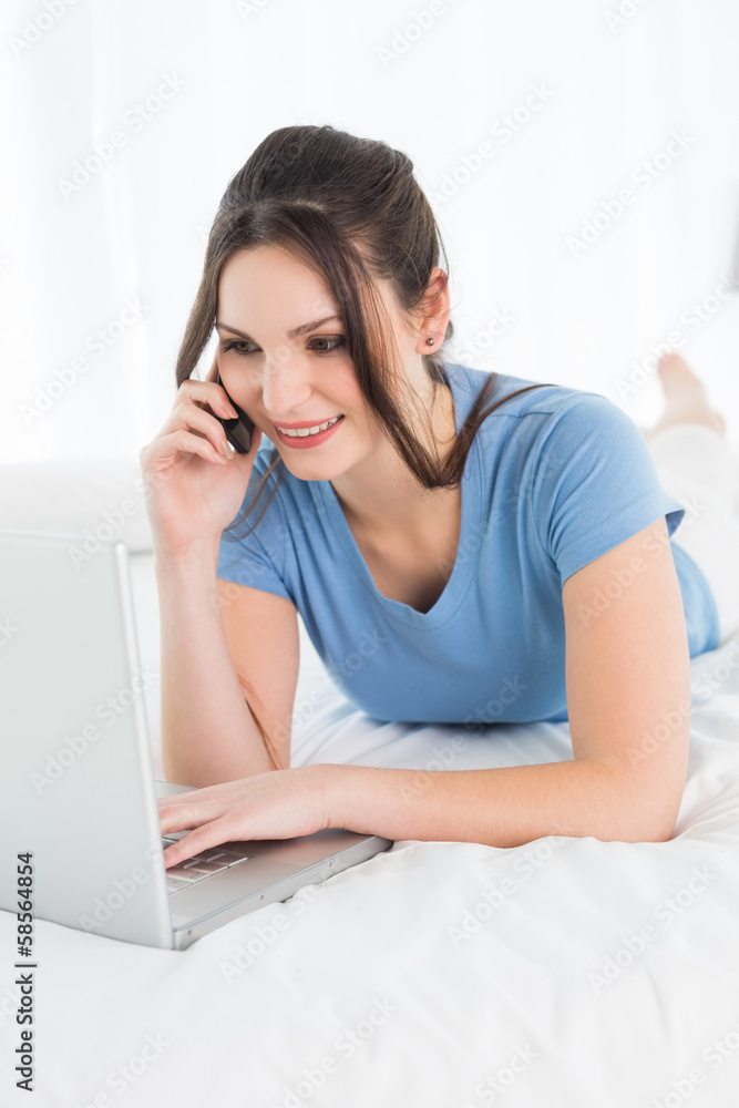 Woman using mobile phone and laptop in bed Woman using mobile phone and laptop in bed