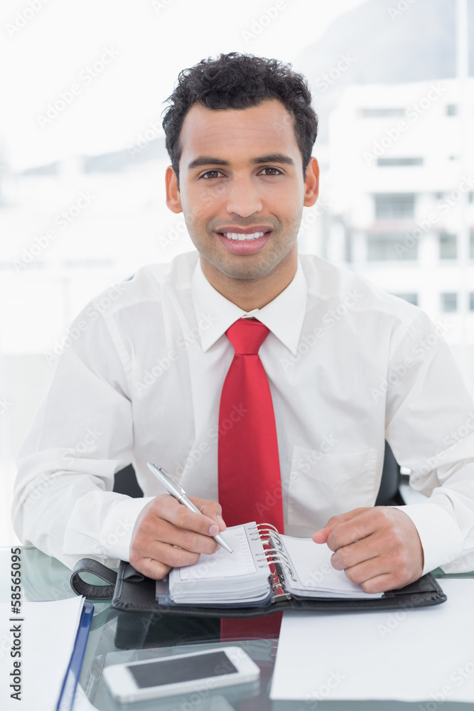 Fototapeta premium Smiling businessman writing in diary at office