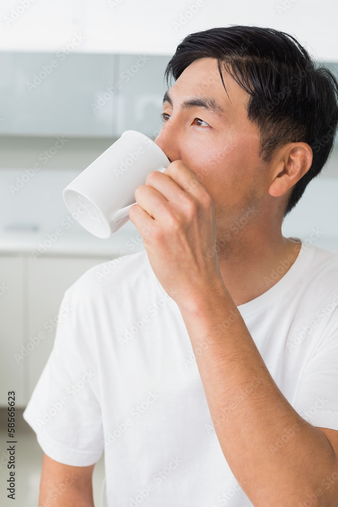 Serious man drinking coffee as he looks away in kitchen Serious man drinking coffee as he looks away in kitchen