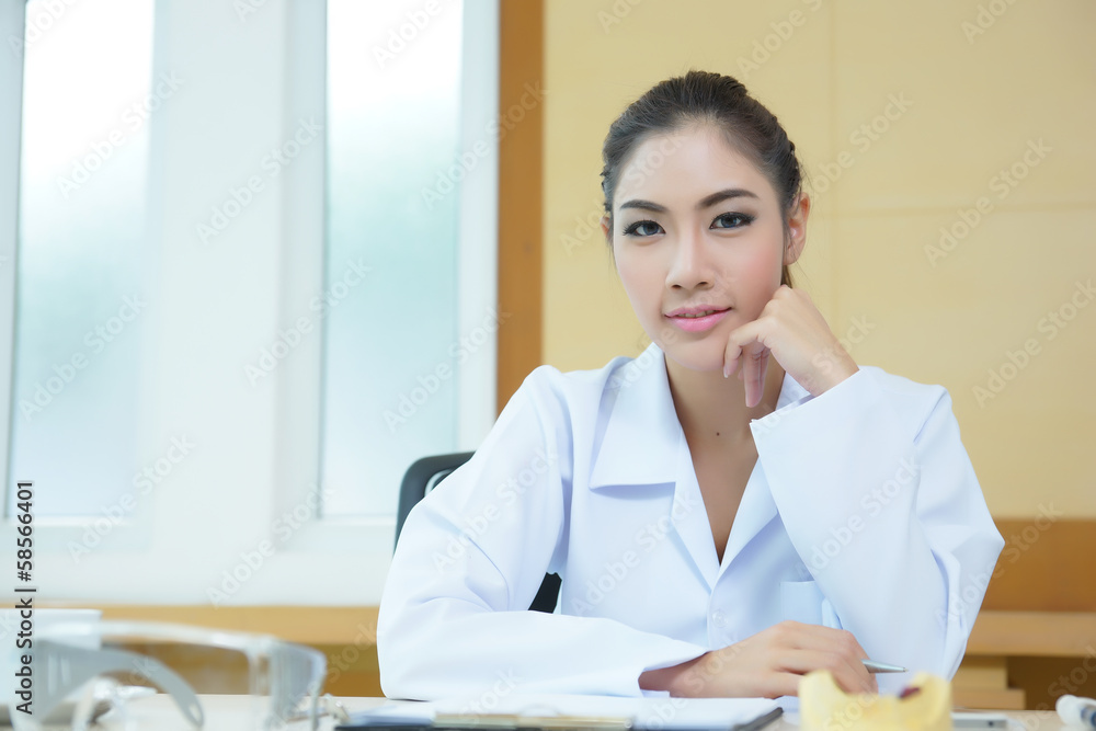 Attractive young female doctor sitting at desk in office Attractive young female doctor sitting at desk in office