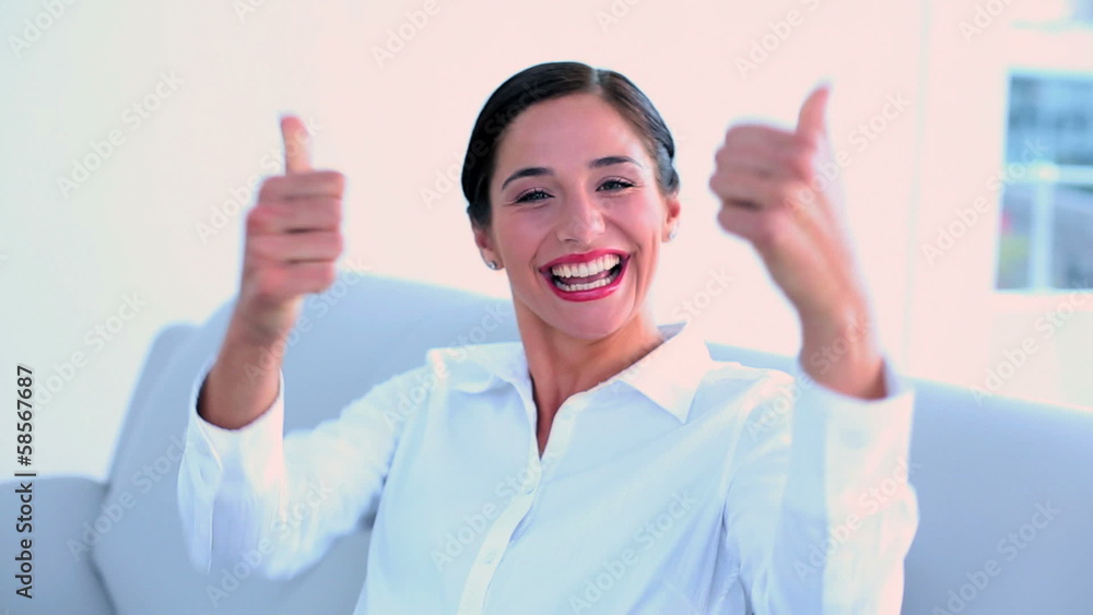 Successful businesswoman sitting on couch and giving thumbs up Successful businesswoman sitting on couch and giving thumbs up
