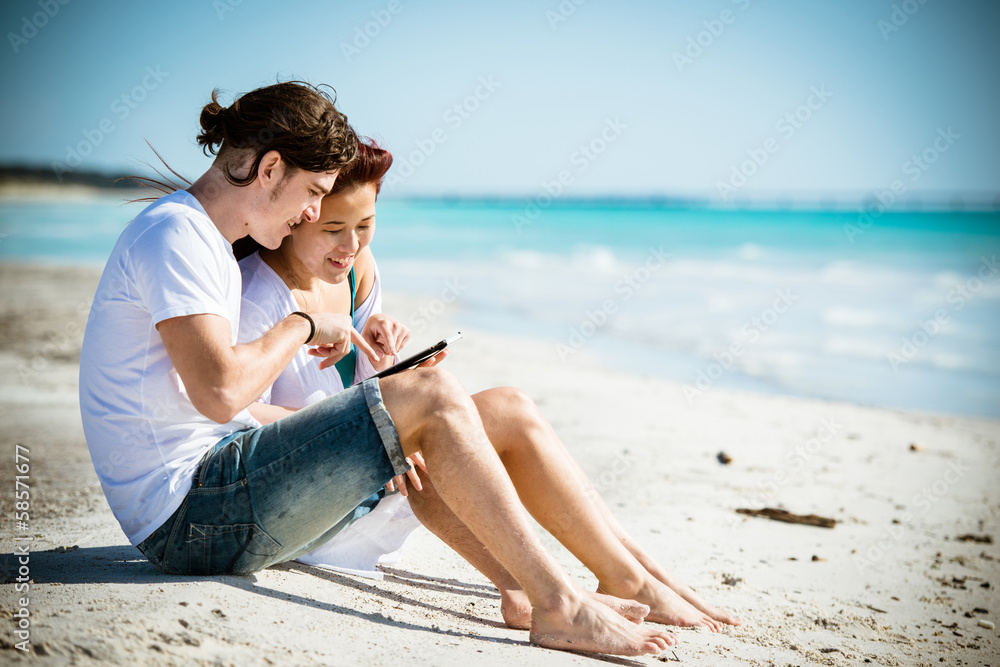 Couple togetherness surfing with tablet on the beach