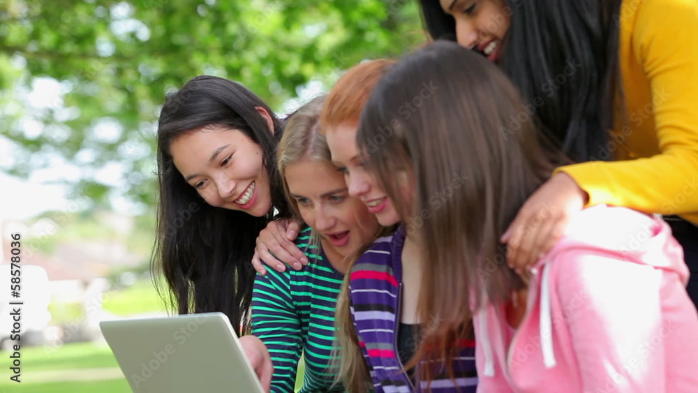 Female students looking at the laptop together outside