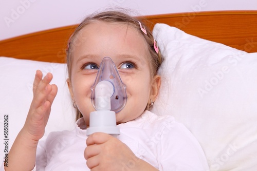 Happy little girl making aerosol treatment