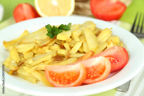 Ruddy fried potatoes on plate on wooden table close-up