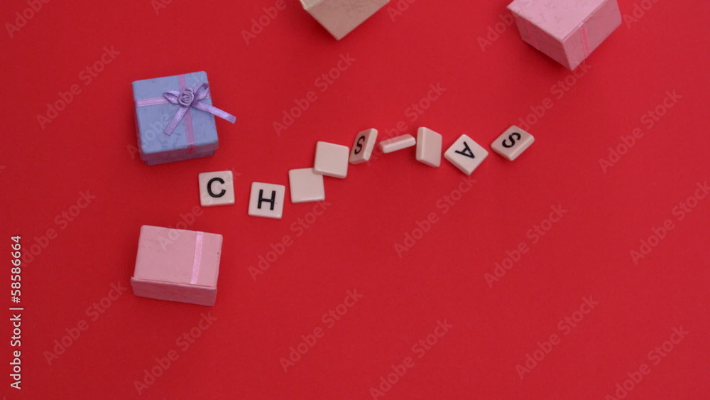 White letter tiles moving to spell out christmas with presents White letter tiles moving to spell out christmas with presents