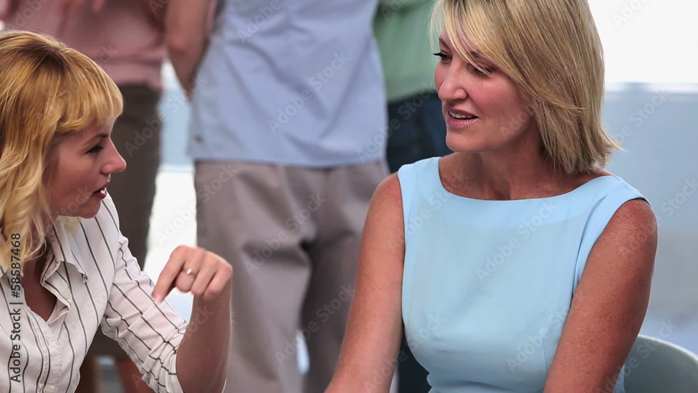 Businesswoman writing notes as colleague speaks Businesswoman writing notes as colleague speaks