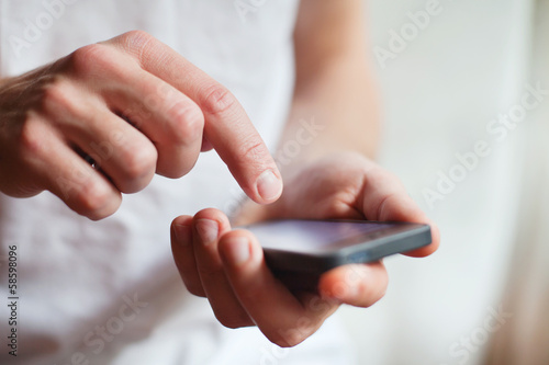 man hands touching smartphone bright background, closeup
