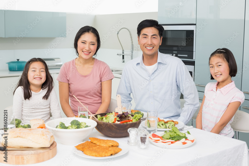 Happy family of four enjoying healthy meal in kitchen Happy family of four enjoying healthy meal in kitchen