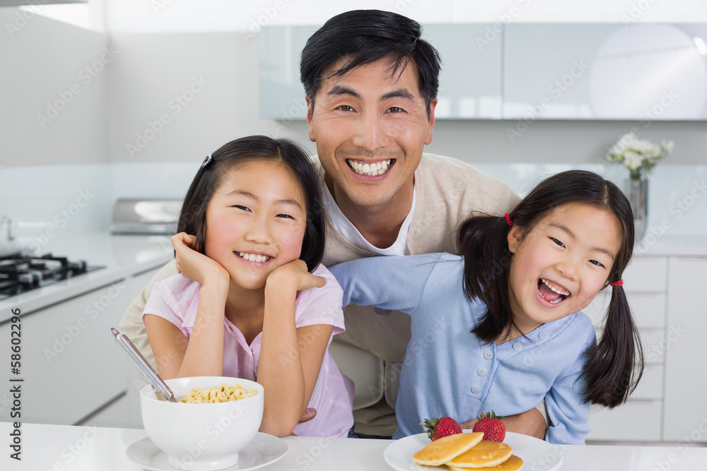 Smiling man with happy daughters having breakfast in kitchen Smiling man with happy daughters having breakfast in kitchen
