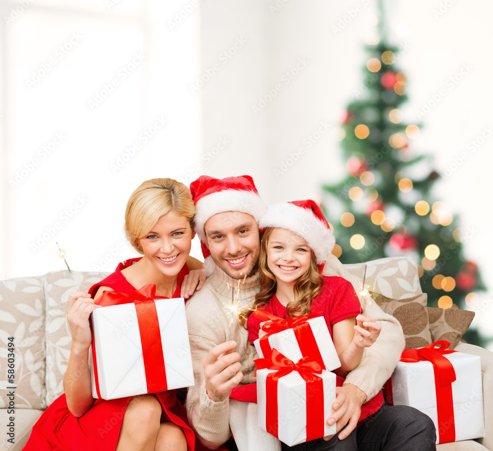 smiling family holding gift boxes and sparkles smiling family holding gift boxes and sparkles