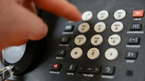 Finger is pushing the phone number buttons.