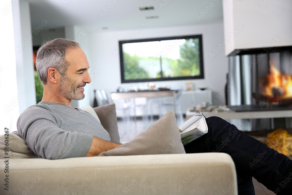 Senior man reading newspaper by fireplace Senior man reading newspaper by fireplace