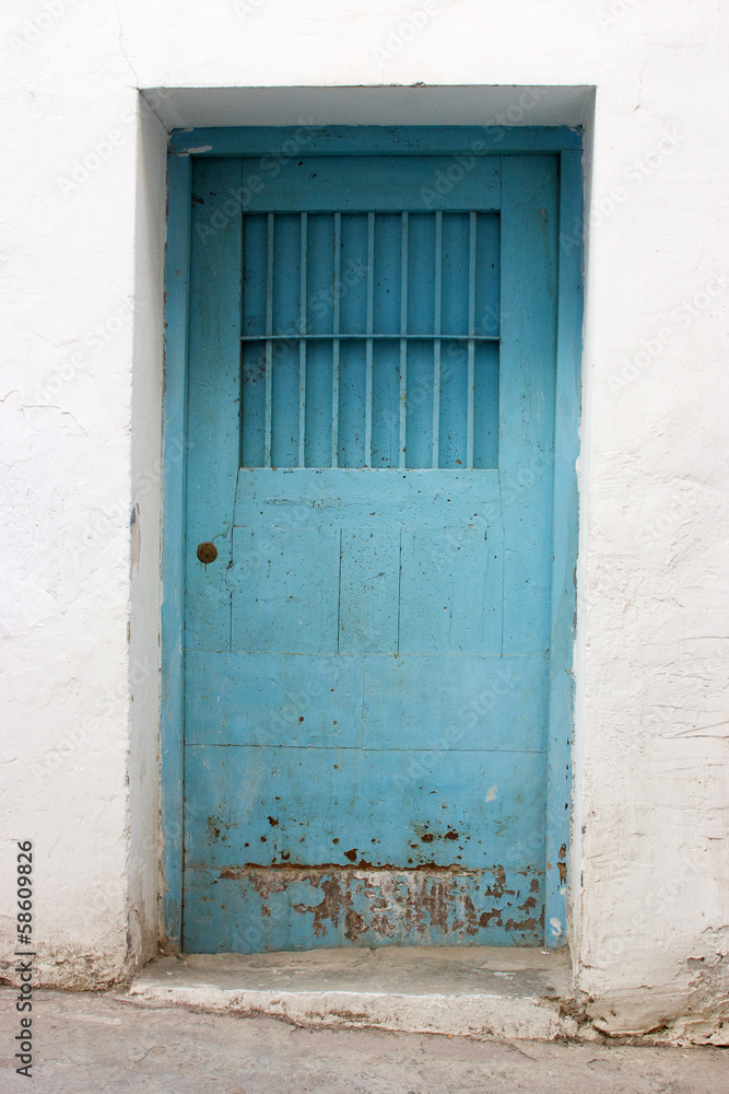 Puerta vieja azul en pared blanca