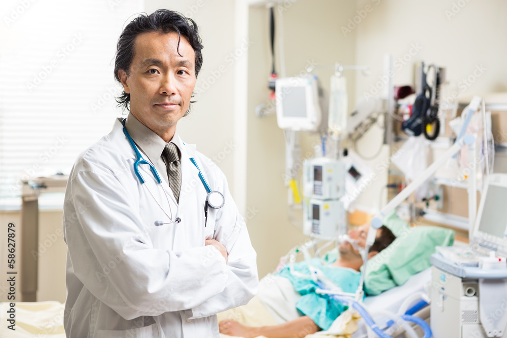 Confident Doctor With Patient Resting In Background Confident Doctor With Patient Resting In Background