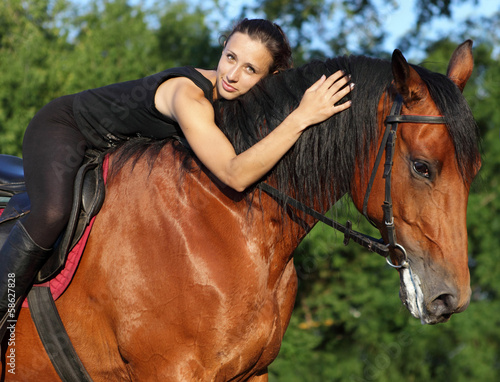Young attractive equestrian woman hugging a horse