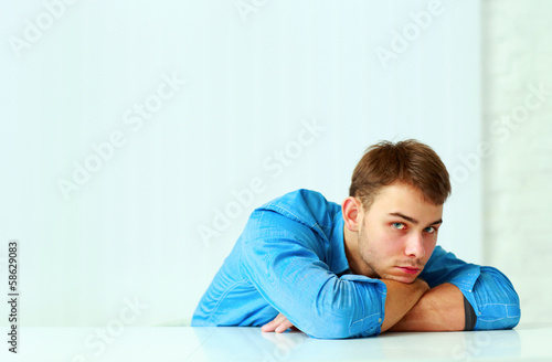 Young pensive businessman laying on the table