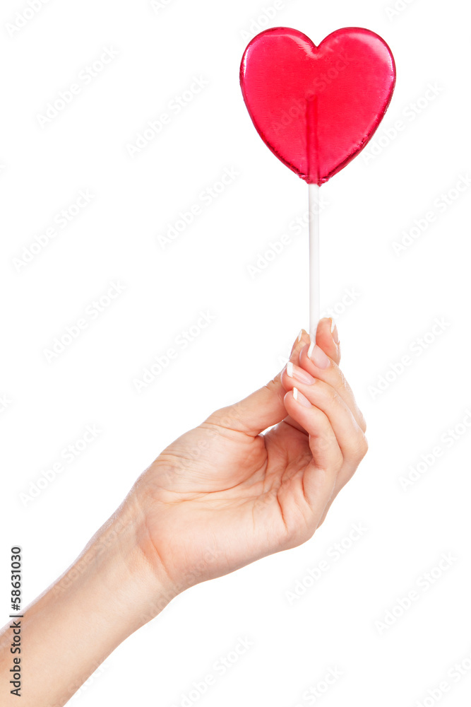 Female hand holding a heart-shaped lollipop