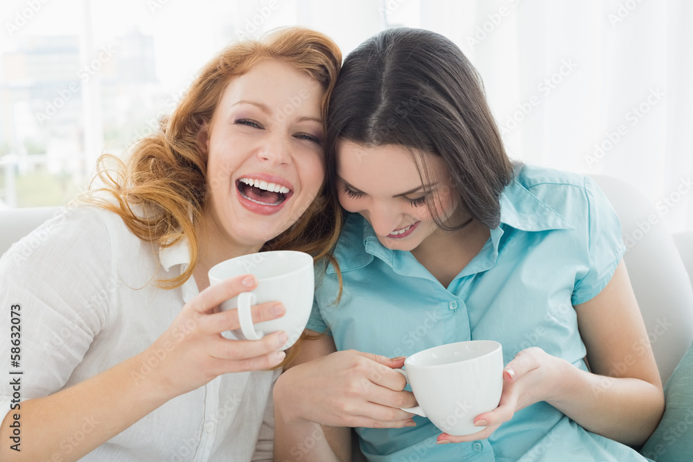 Friends with coffee cups enjoying a conversation at home Friends with coffee cups enjoying a conversation at home