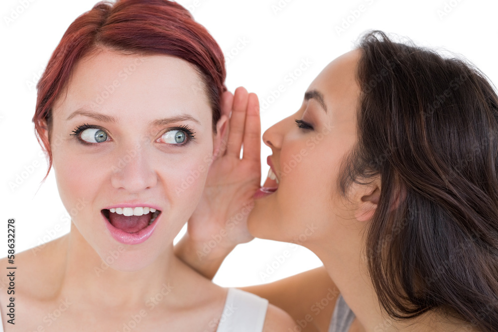 Close-up of two young female friends gossiping Close-up of two young female friends gossiping