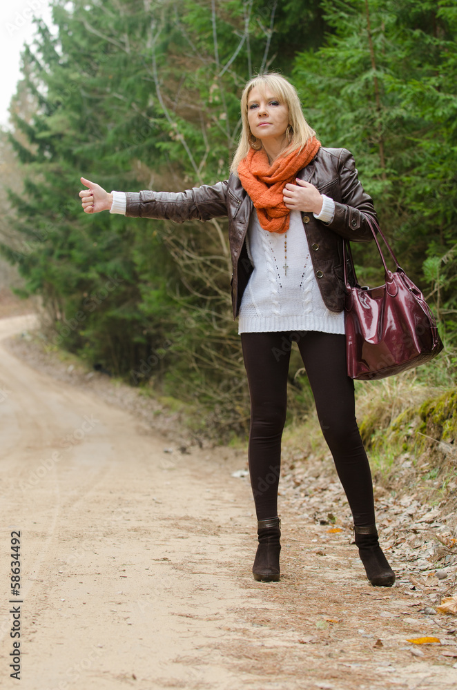 Pretty girl hitchhiking in the forest