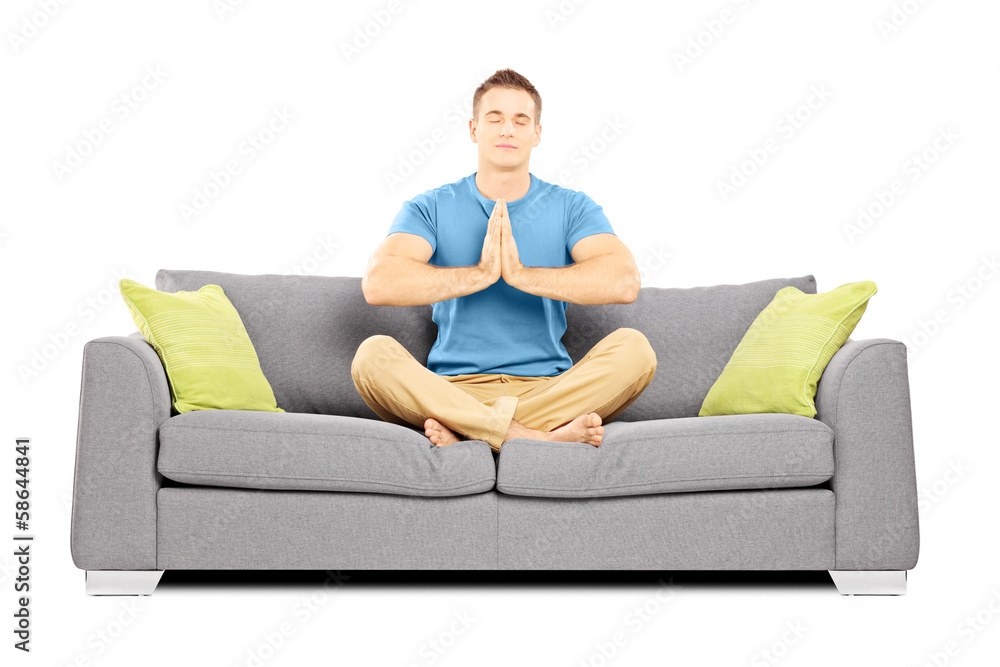 Young male meditating seated on a sofa Young male meditating seated on a sofa